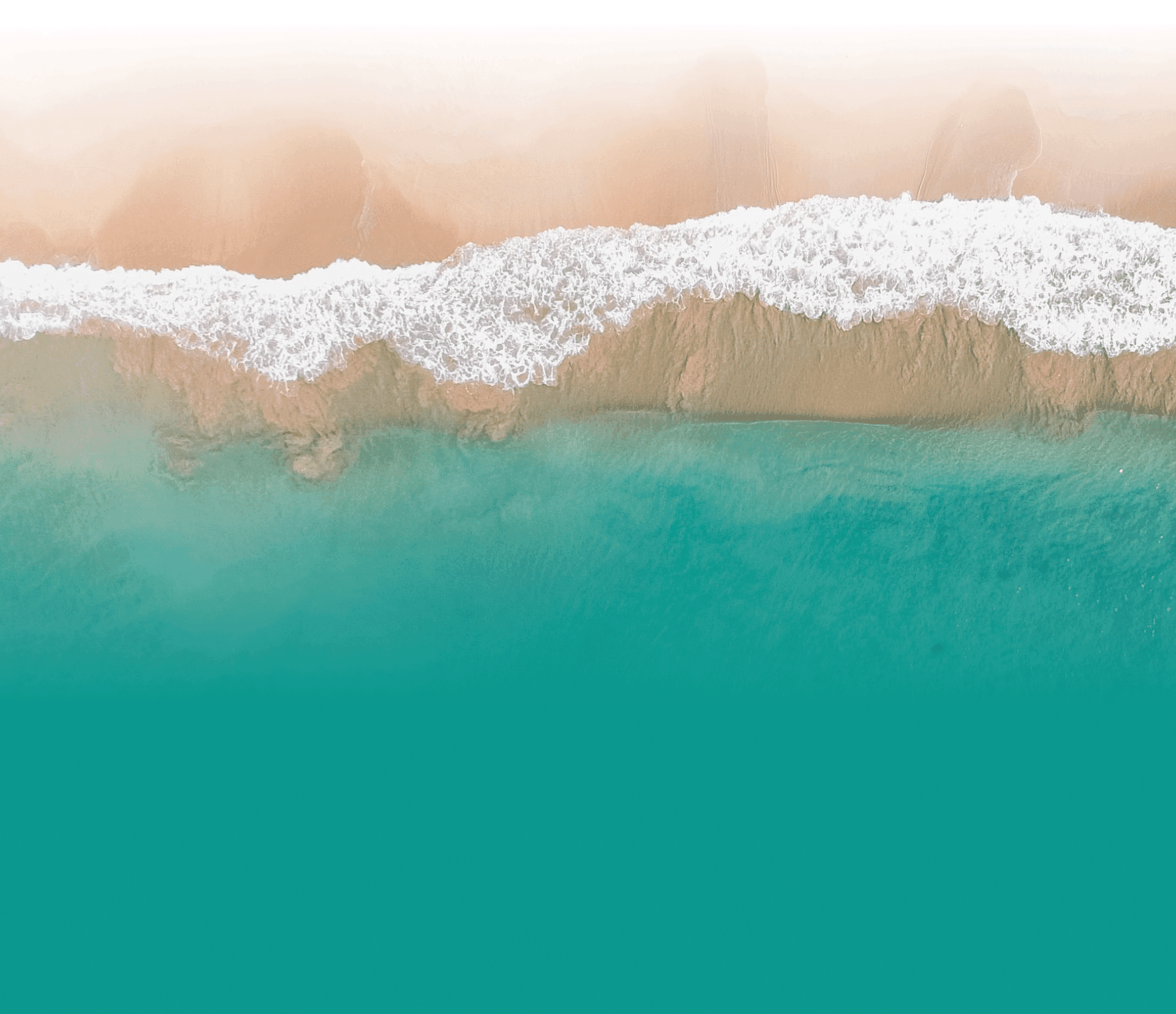 Aerial view of a calm turquoise sea meeting a soft sandy shore